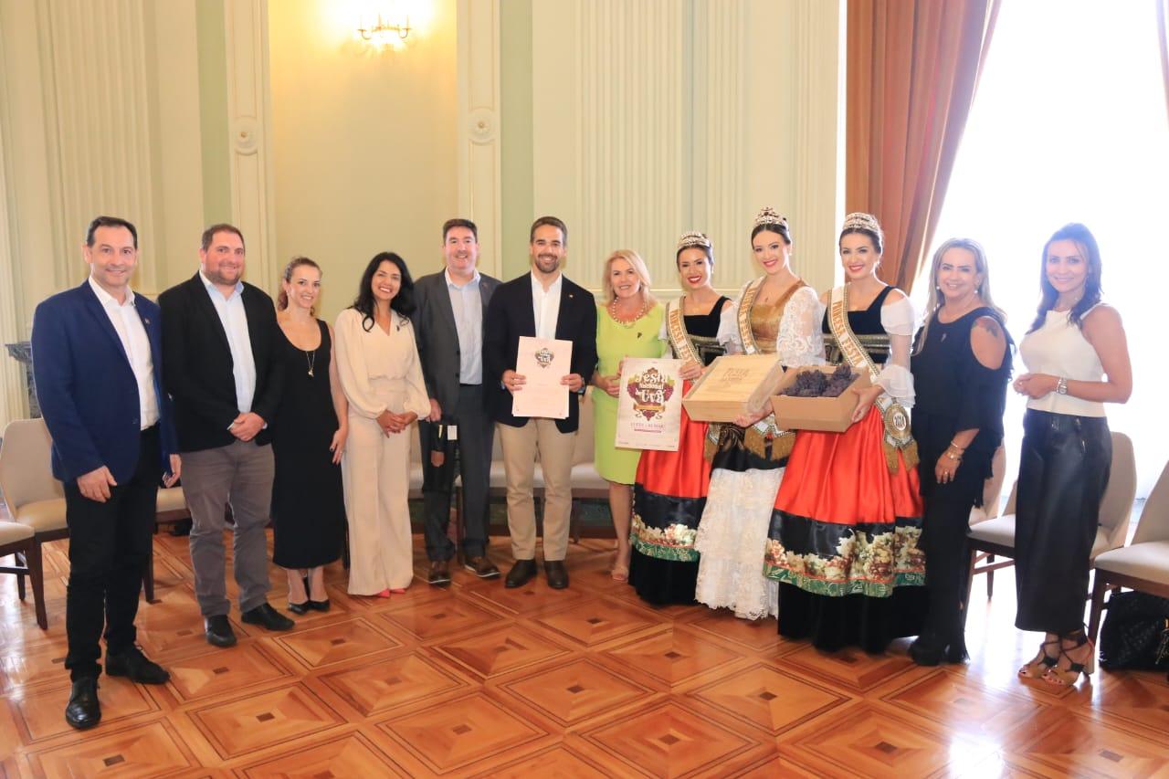 Junto à comitiva caxiense, Marisol Santos, vice-presidente da Festa da Uva, entrega convite oficial do evento para o governador Eduardo Leite